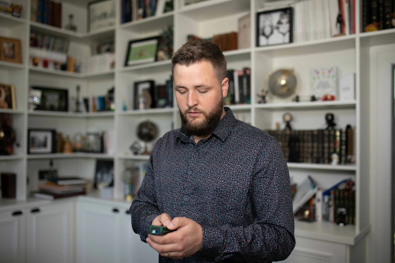 Jean Yoder consultant son téléphone devant une bibliothèque